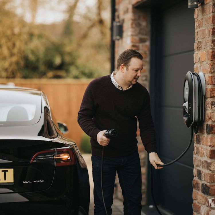 Man charging EV at home outside his garage using the zappi EV charger in black